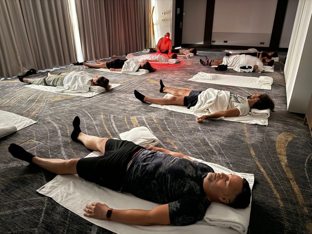 Diverses persones en una sessió d'acupuntura comunitària amb la terapeuta atenent una pacient
