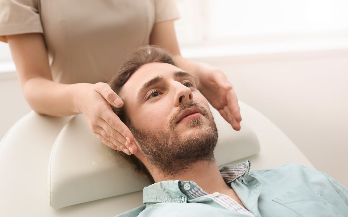 Home rebent una sessió de Reiki amb imposició de mans al cap